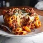 A delicious slice of Baked Ziti with melty cheese, rich sauce, and ground meat.