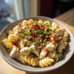 A bowl of creamy Chicken Bacon Ranch Pasta topped with crispy bacon bits and fresh green onions.