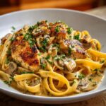 A close-up of Chicken Mushroom Pasta with Creamy Herbs, featuring tender chicken pieces, sautéed mushrooms, and fettuccine pasta coated in a rich, herb-infused cream sauce.