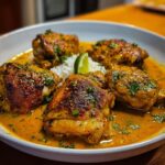 A bowl of delicious Chicken Thighs in Coconut Curry Sauce served with white rice and a lime wedge.