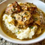 A bowl of Comfort Style Chicken with Creamy Gravy served over fluffy mashed potatoes, garnished with parsley.