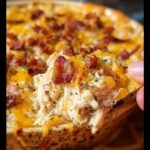 Close-up of a scoop of Crack Chicken Style Dinner Bowl, showing shredded chicken, melted cheese, and crispy bacon bits.
