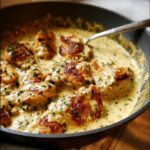 Close-up of pan-seared chicken pieces coated in a creamy ranch sauce, garnished with parsley.