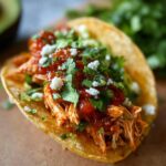 A delicious taco filled with shredded Fast Salsa Chicken, topped with salsa, cilantro, and cheese.