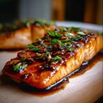 Close-up of a glistening Honey Soy Glazed Salmon fillet with a sticky finish, topped with green onions and sesame seeds.