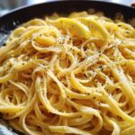 Close-up of Lemon Parmesan Pasta with Fresh Zest, featuring linguine noodles coated in a creamy sauce, topped with lemon slices and herbs.