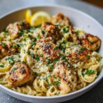A bowl of Pot Chicken Pasta with Garlic Butter, topped with grilled chicken pieces, parsley, and grated cheese.