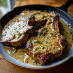 Juicy smothered pork chops served in a creamy onion gravy, garnished with fresh parsley.
