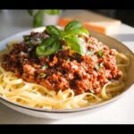A bowl of fettuccine pasta topped with rich Turkey Bolognese Sauce and fresh basil.