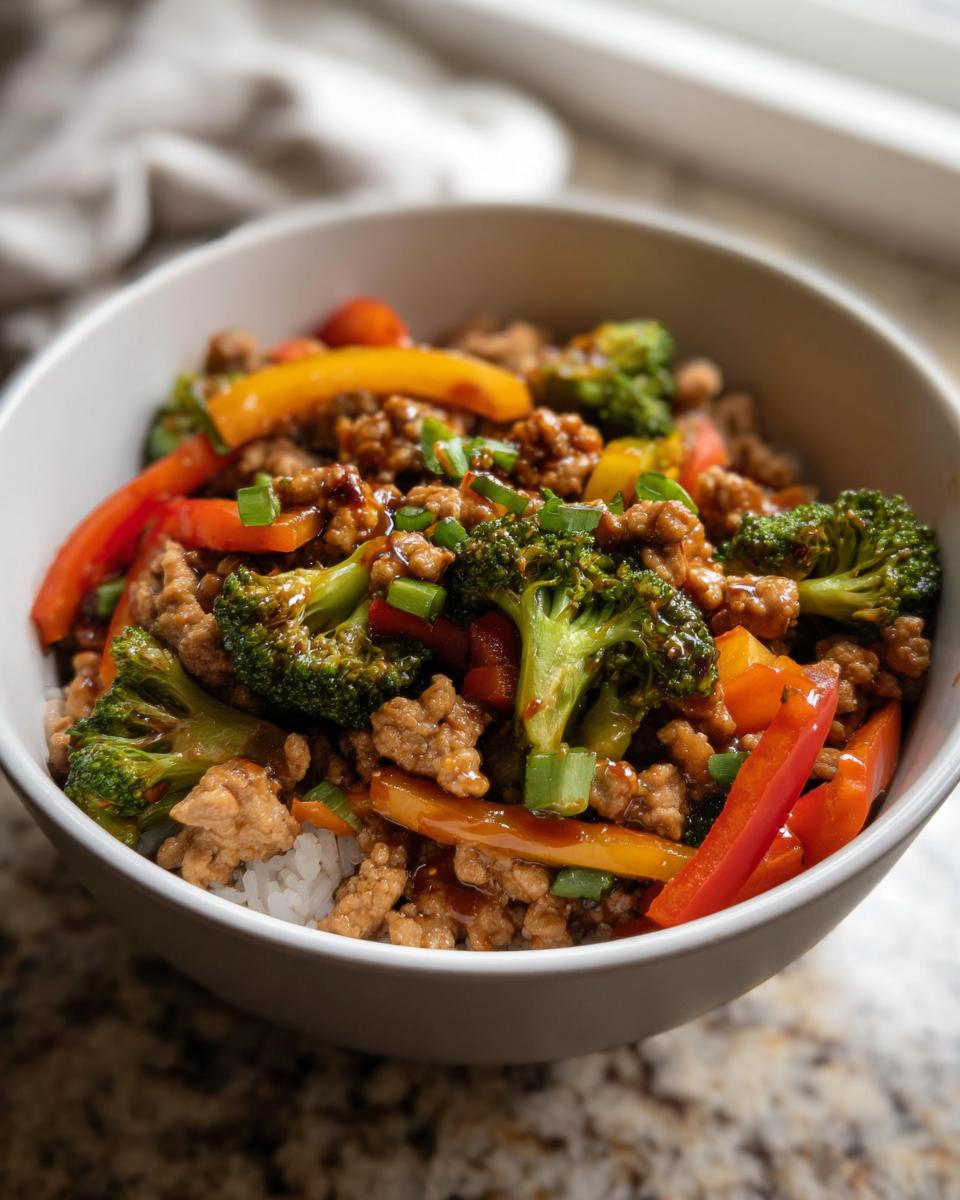 A bowl of Turkey Stir Fry with Sweet and Savory Sauce, featuring ground turkey, broccoli, bell peppers, and scallions over rice.