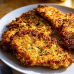 A plate of Zesty Parmesan Chicken with Crispy Edges, golden brown and sprinkled with parsley.