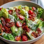 A close-up of a BLT Salad Recipe in a bowl, featuring crisp romaine lettuce, cherry tomatoes, and crispy bacon bits with creamy dressing.
