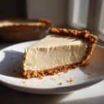 A perfect slice of creamy peanut butter pie with a graham cracker crust on a white plate.