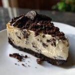 A decadent slice of No Bake Oreo Cheesecake, topped with crushed Oreos and whole Oreo cookies.