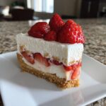 A slice of No Bake Strawberry Delight dessert with fresh strawberries and creamy filling on a white plate.