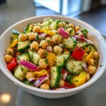 A vibrant bowl of Summer Chickpea Salad with chickpeas, cucumber, red onion, and bell peppers, tossed with herbs.